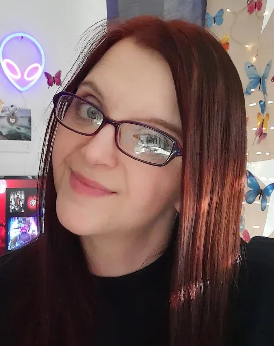 Porträt von Janine Zachariae mit roten Haaren und Brille in ihrem Arbeitszimmer